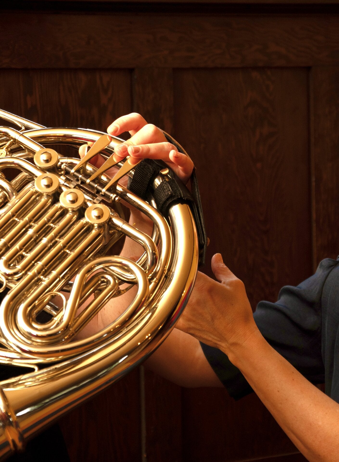 A French horn musician demonstrating instrument position
